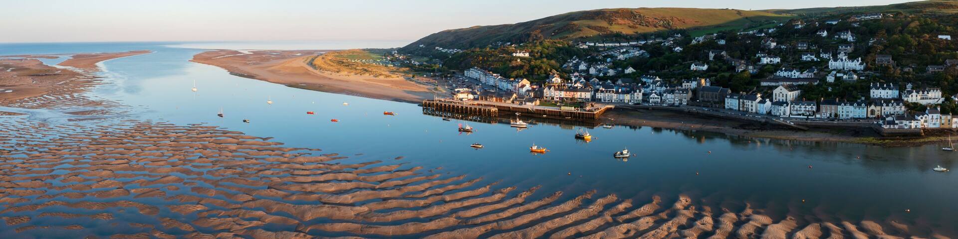 A coastal town with a pier, boats, and a sandy beach.
