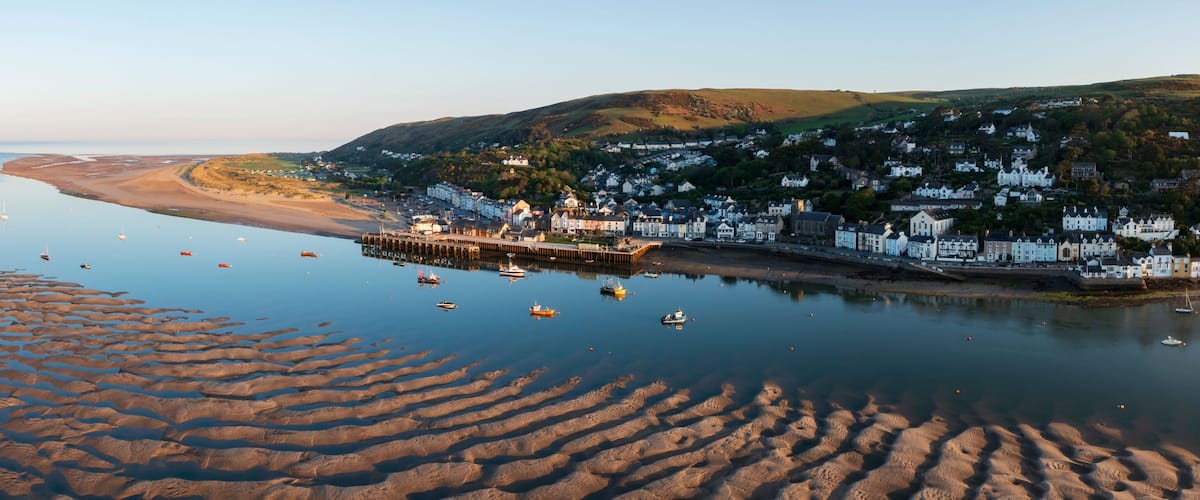 A coastal town with a pier, boats, and a sandy beach.