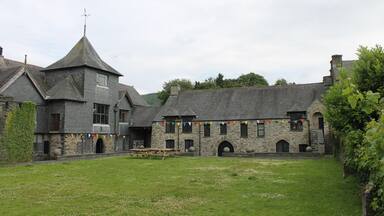 A stone building with a tower, picnic tables, and colorful flags.