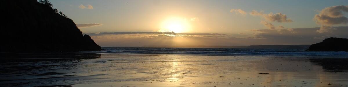 Sun setting over Plymouth from Hope Cove Beach.