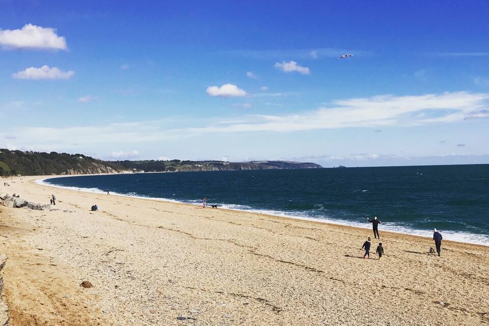 Una playa arenosa con el océano y un cielo azul despejado.