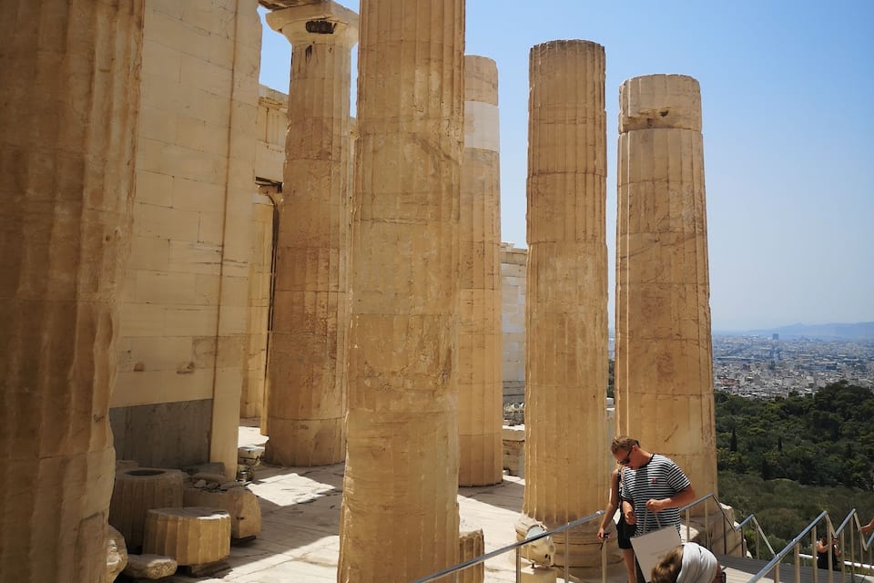 Ancient stone columns and a cityscape in the background.