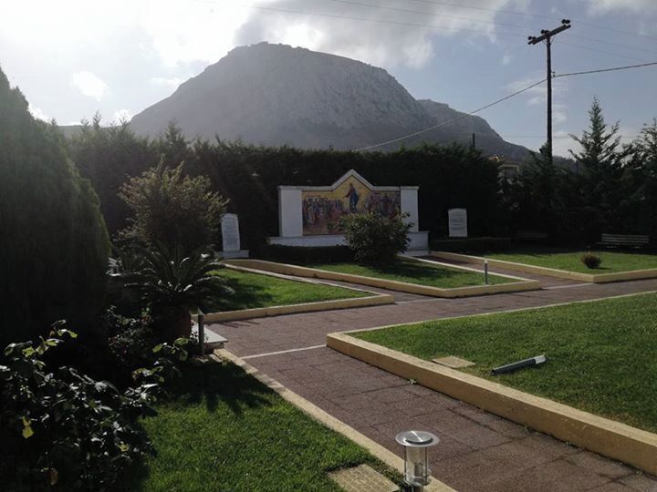 A landscaped area with a pathway, a small building with a mural, and a mountain in the background.