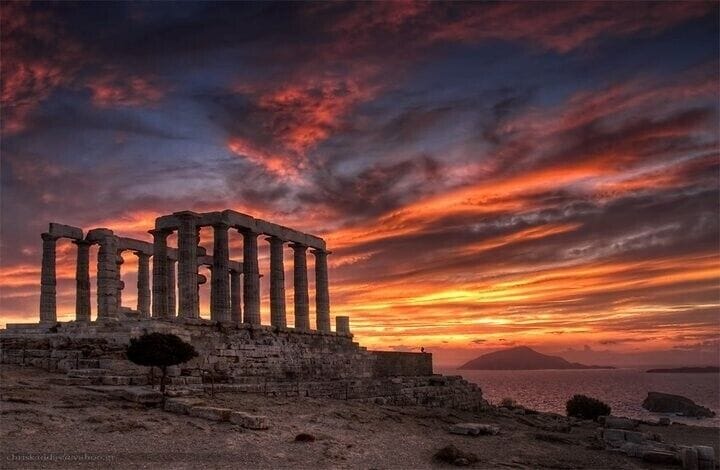 Ancient ruins with columns, set against a sunset sky.