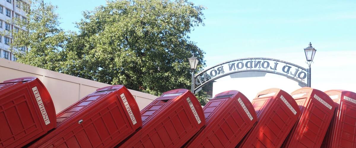 A row of red telephone boxes in front of the Old London Tower.