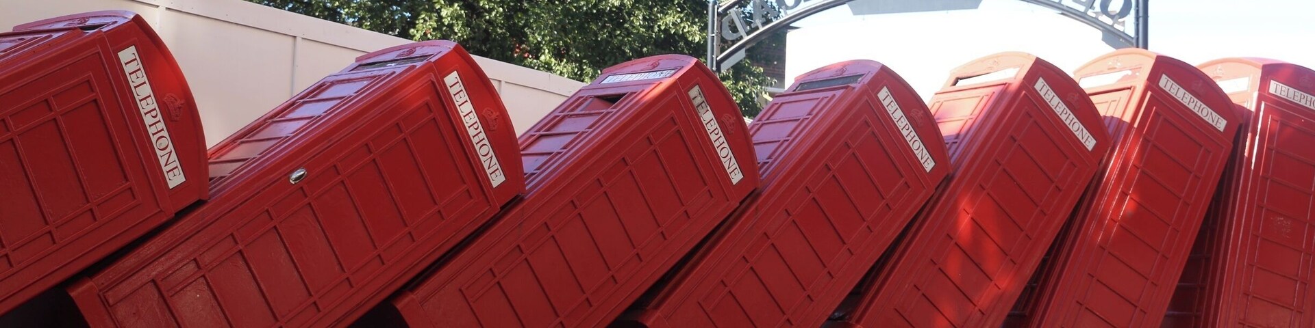A row of red telephone boxes in front of the Old London Tower.
