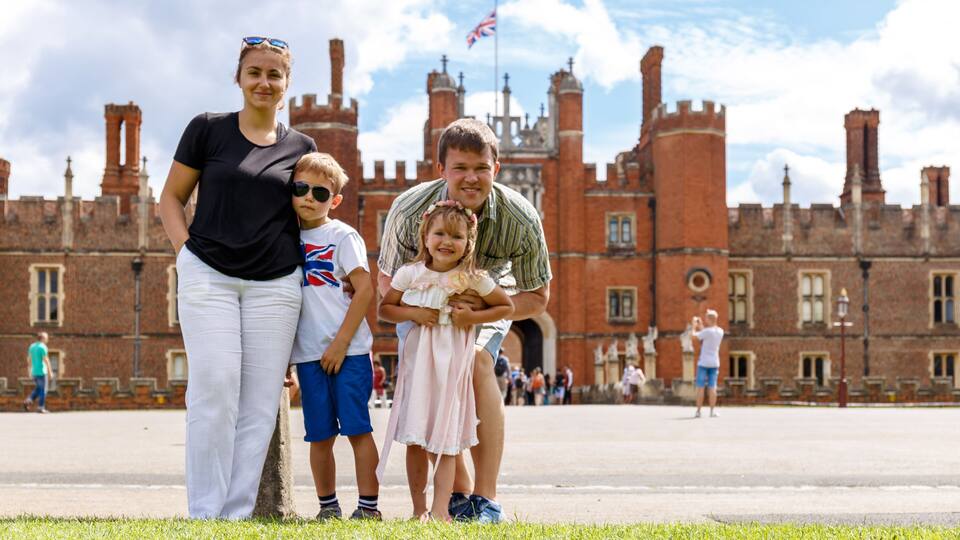 A family in front of a historic castle with red brick walls and towers.
