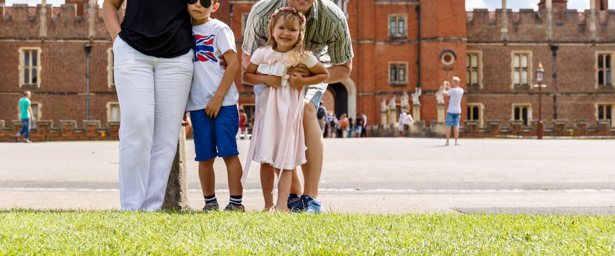 A family in front of a historic castle with red brick walls and towers.