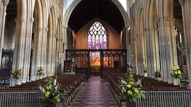 A cathedral interior with high vaulted ceilings, arched windows, and rows of pews.