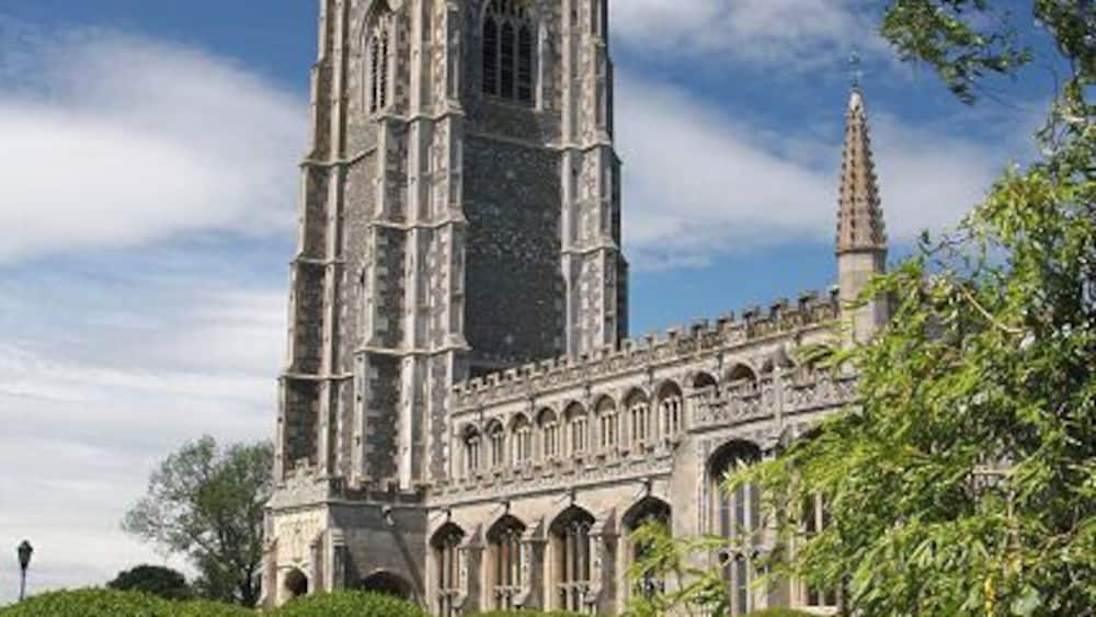 A historic cathedral with a tall tower and a spire, surrounded by lush greenery.
