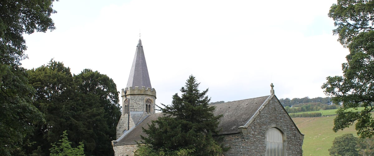 A stone church with a pointed steeple and a graveyard.