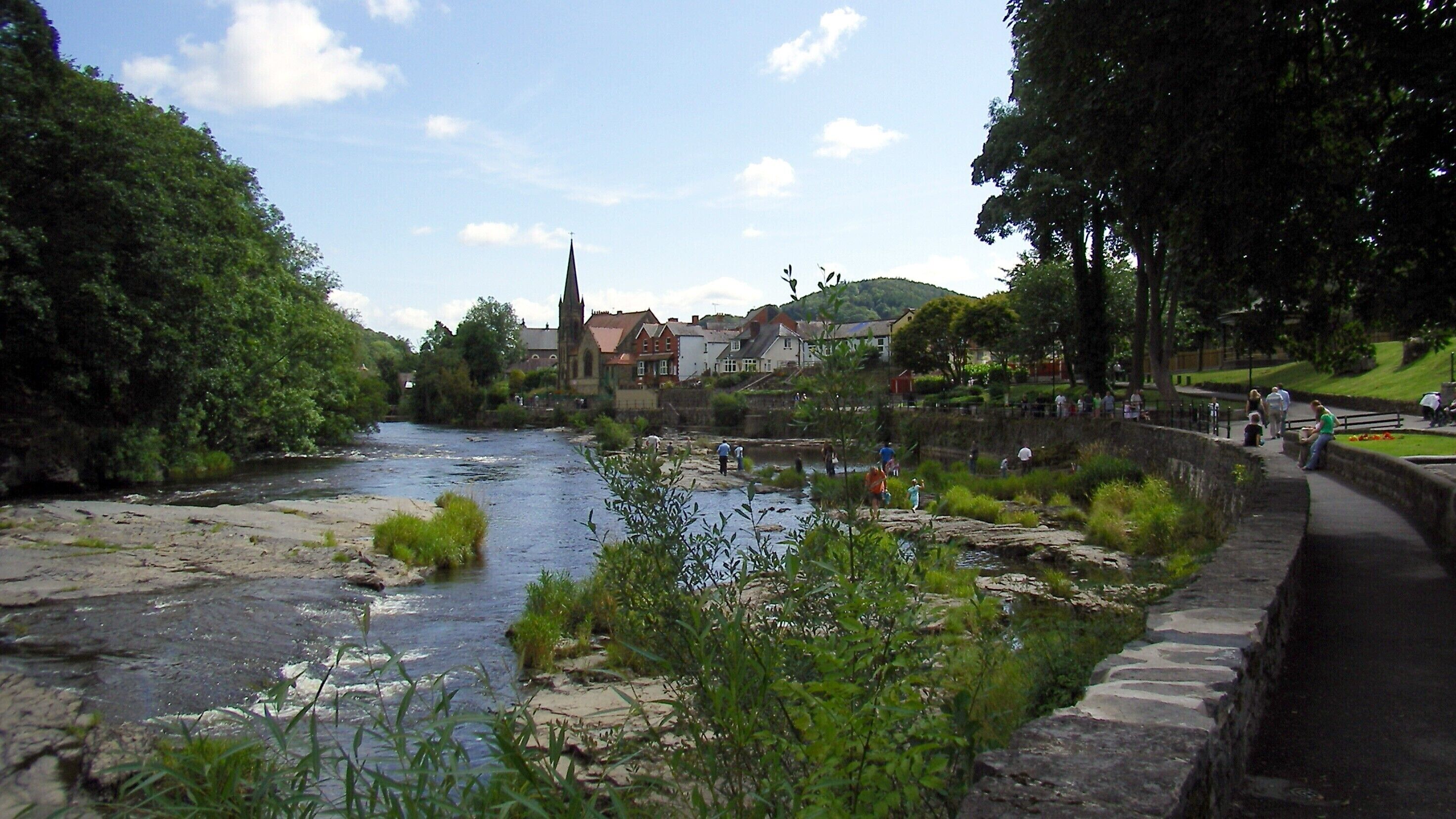 Un río que atraviesa un pueblo con una iglesia y casas al fondo.