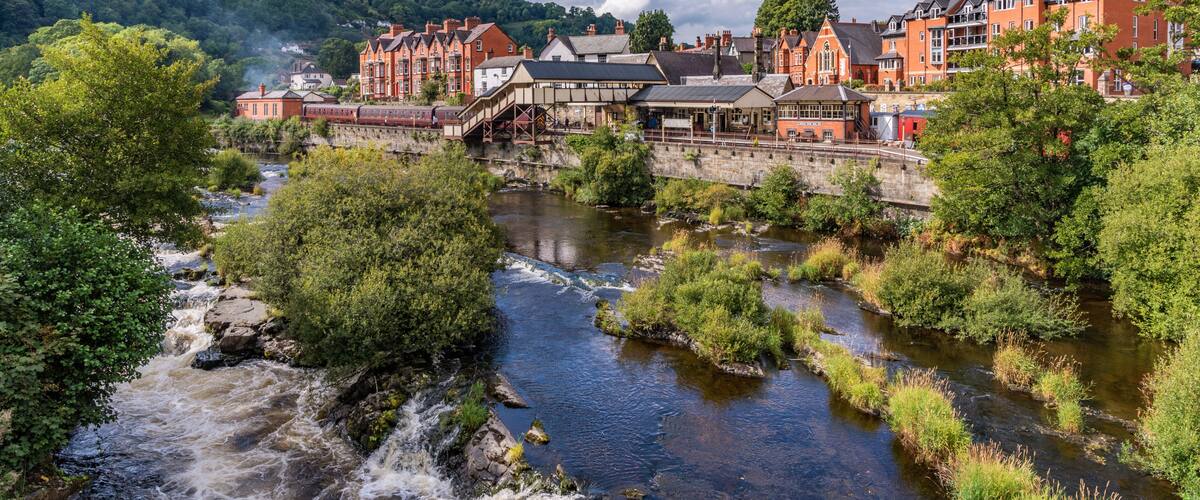 A river flowing through a town with historic buildings and a bridge.