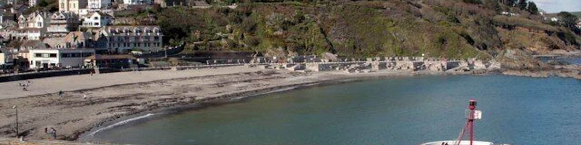 Un pueblo costero con un faro, una playa y casas en una colina.