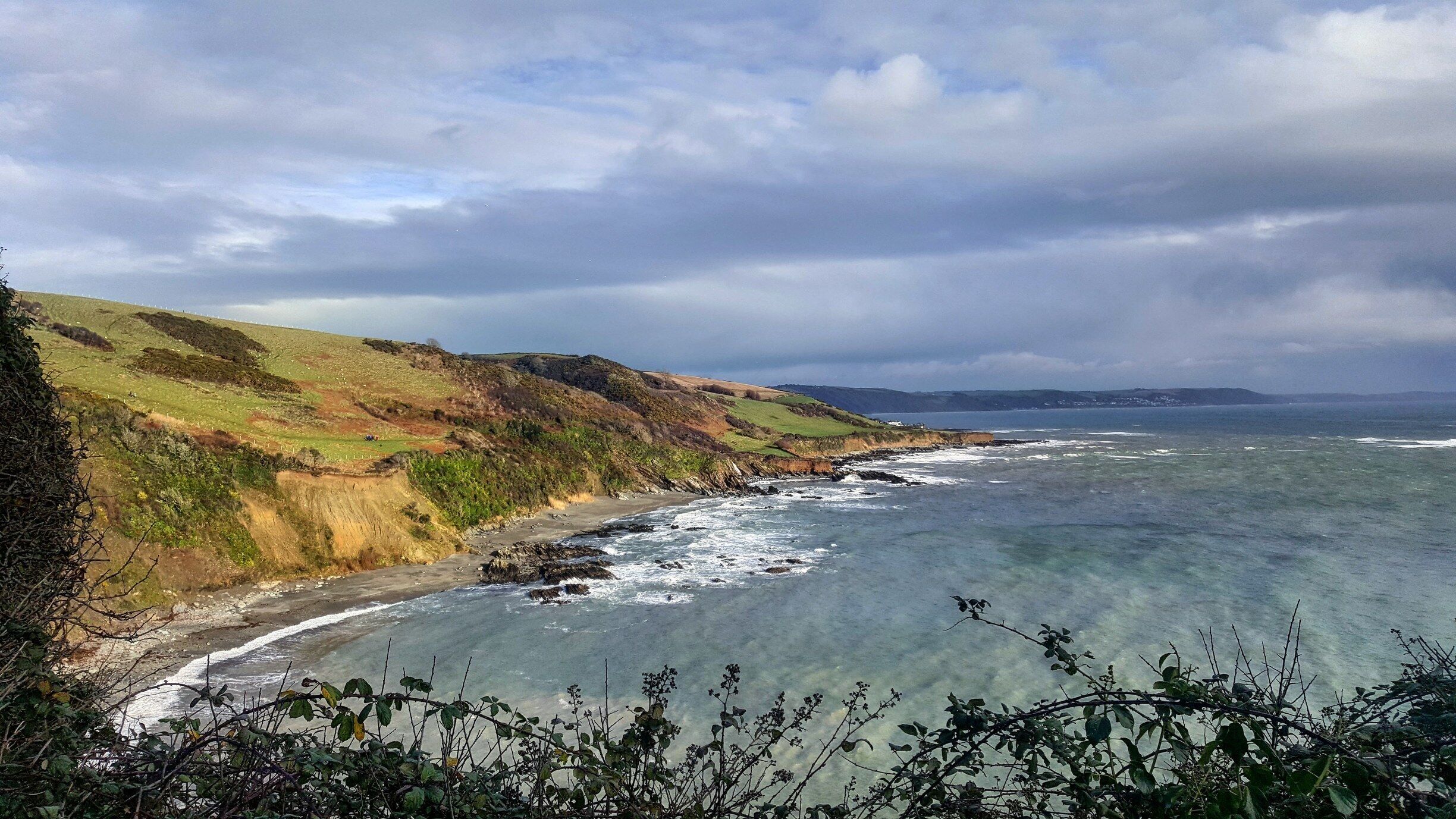 A coastal landscape with cliffs, a beach, and the ocean.