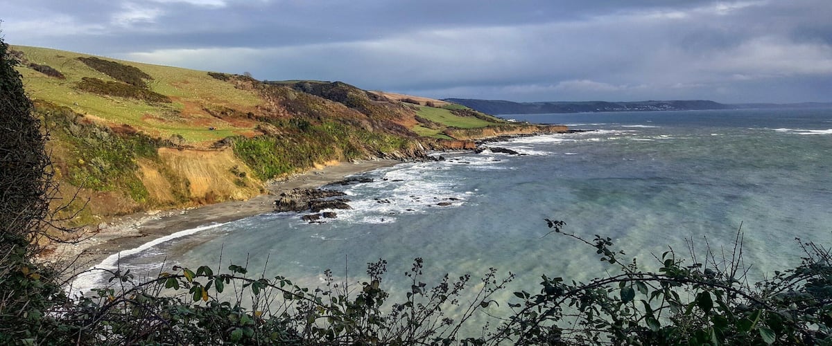 A coastal landscape with cliffs, a beach, and the ocean.