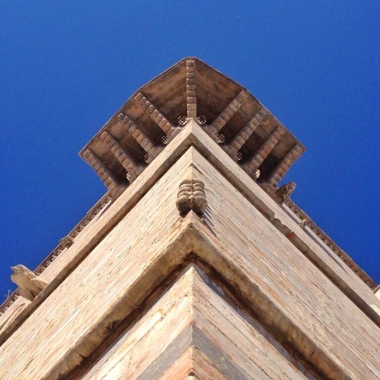 A stone structure with a pointed roof and a carved lion head at the base.