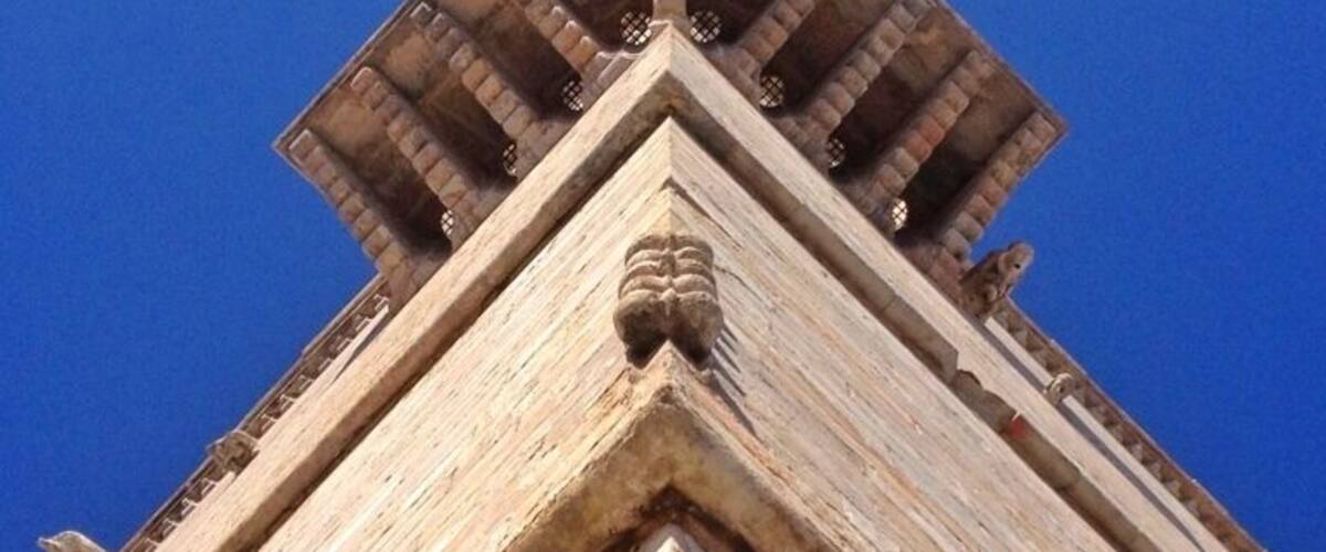 A stone structure with a pointed roof and a carved lion head at the base.