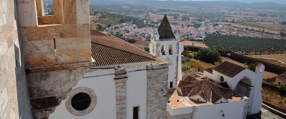 A historic fortress with a prominent tower and a panoramic view of a town and countryside.