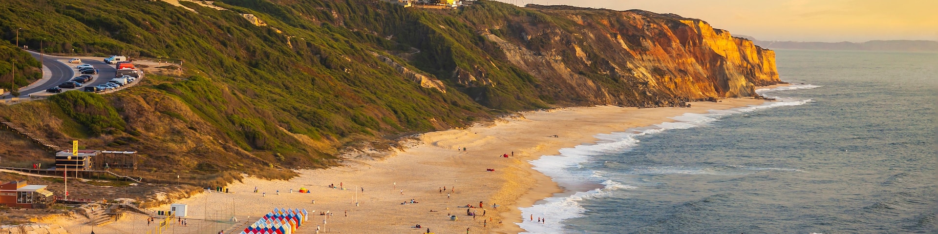 Paisaje costero con playa, acantilados y una carretera con vehículos.