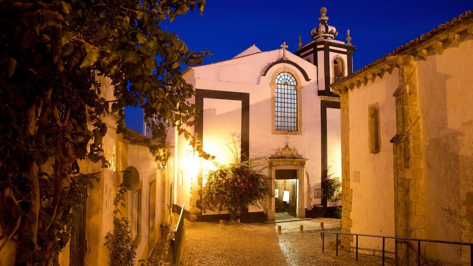 A historic church with a bell tower and arched windows, surrounded by cobblestone streets and ivy-covered walls.