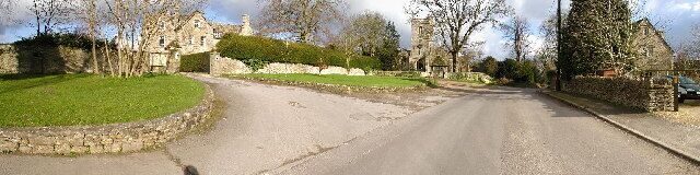 A rural road with stone walls and a large house in the background.