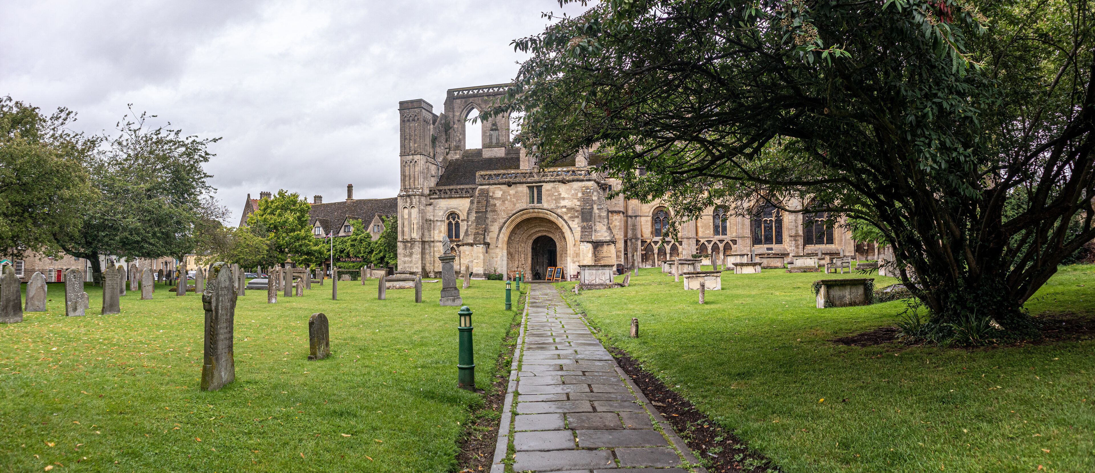 A historic church with a large arched entrance, surrounded by a cemetery with headstones and a pathway leading to the church.