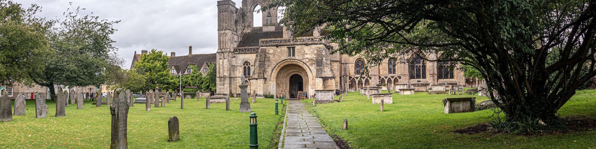 A historic church with a large arched entrance, surrounded by a cemetery with headstones and a pathway leading to the church.