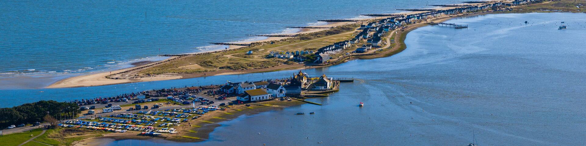 Wide angle aerial panorama of Mudeford sandbar with beach huts and tourists, Dorset, UK