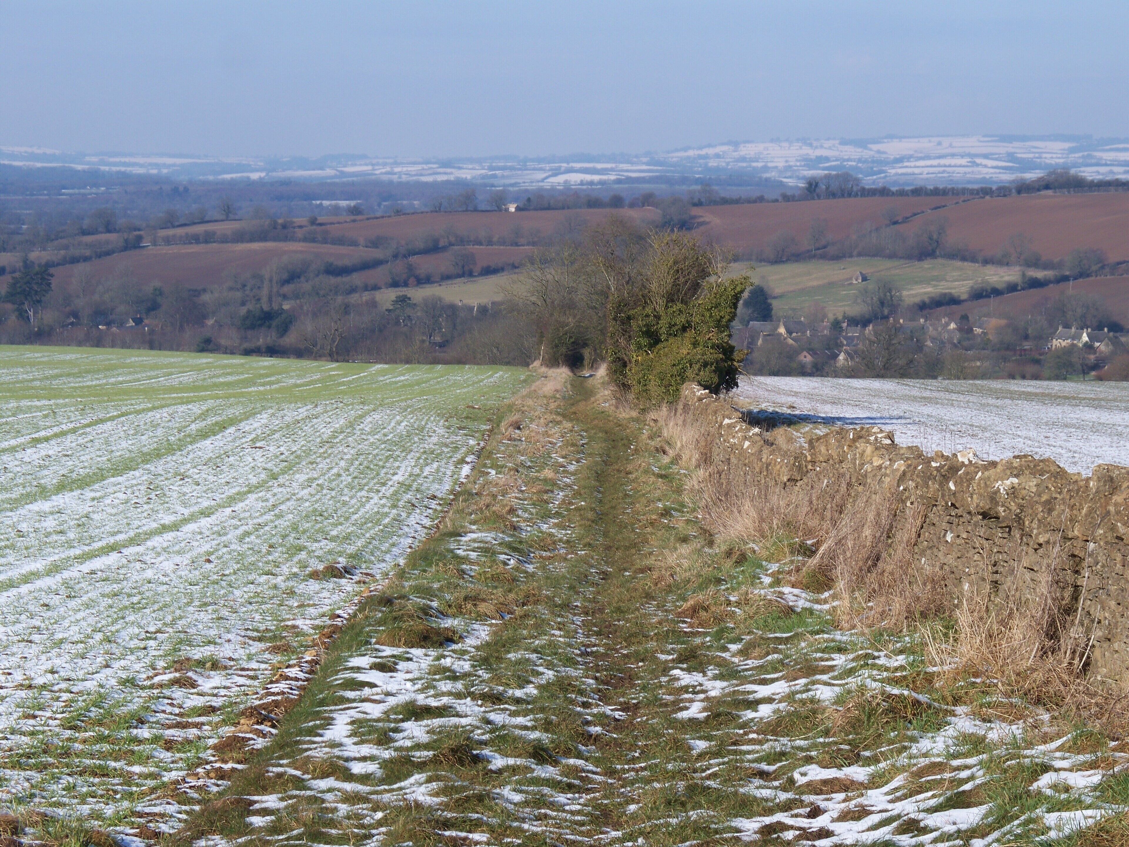 Cross bridleways [4] Near the crest of the ridge, two well-used bridleways meet. One ascends the ridge from Little Compton and ends shortly when it meets the minor road. The other, part of the Macmillan Way long distance path, runs along the ridge and ends shortly when it meets the A44. This is the view looking north west. Little Compton is seen to the right of the image and Ebrington Hill is in the far distance.