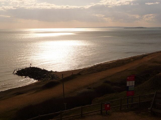A beach with a rocky breakwater and a distant shoreline.
