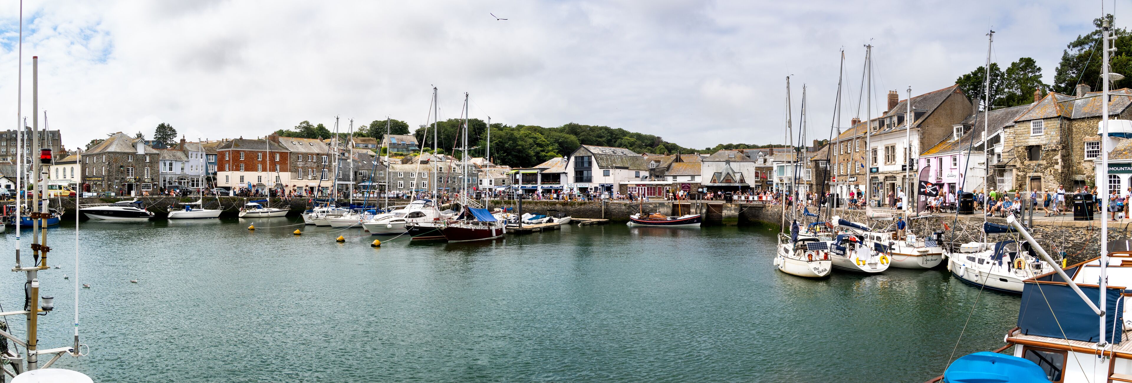 A harbor with numerous boats docked, surrounded by historic buildings and a bridge.