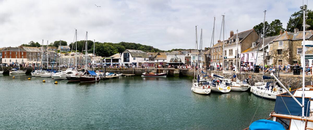 A harbor with numerous boats docked, surrounded by historic buildings and a bridge.