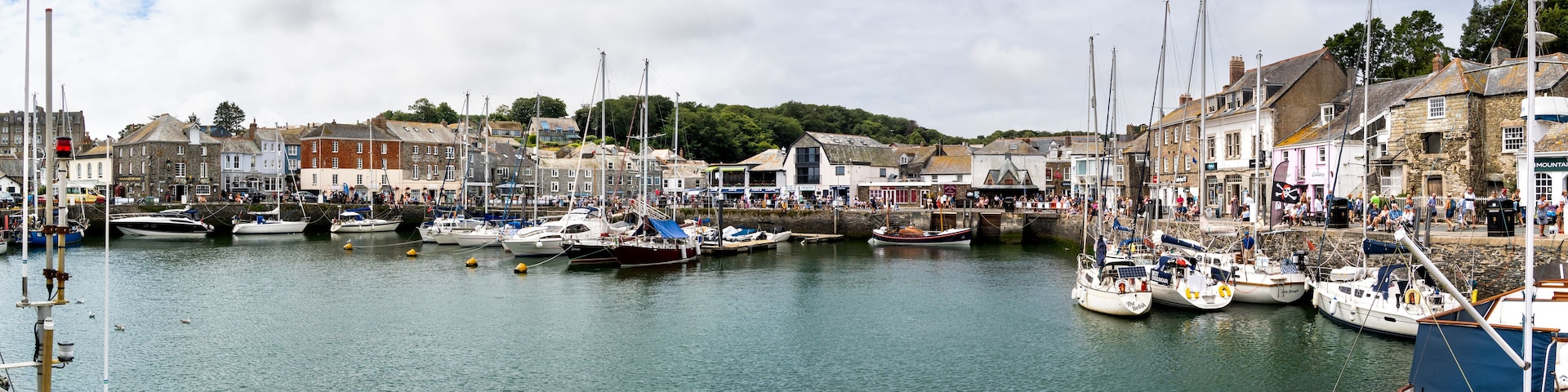 A harbor with numerous boats docked, surrounded by historic buildings and a bridge.