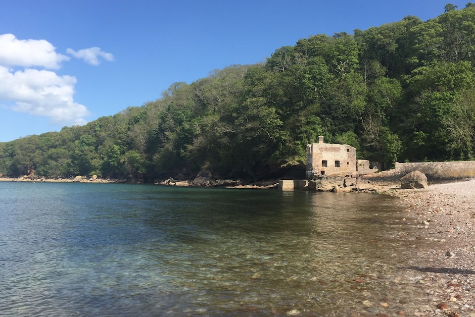 A clear lake with a stone structure on the shore, surrounded by dense forest.