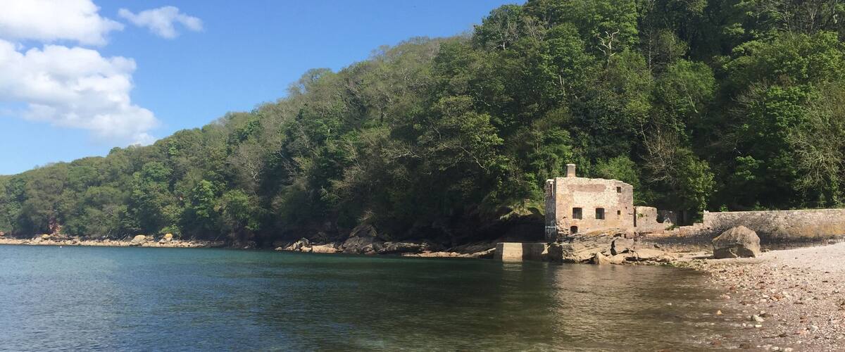 A clear lake with a stone structure on the shore, surrounded by dense forest.