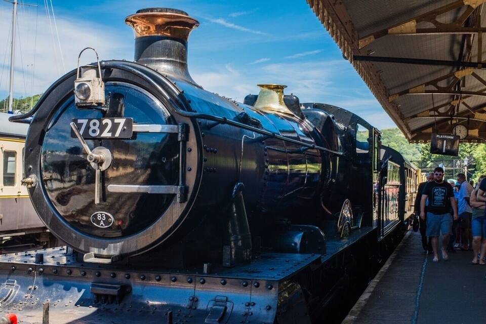 Een oude stoomlocomotief met nummer 7827 staat geparkeerd op een station.
