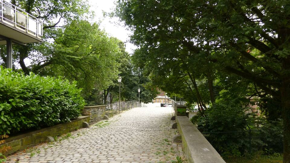 A cobblestone pathway flanked by lush greenery and stone walls.