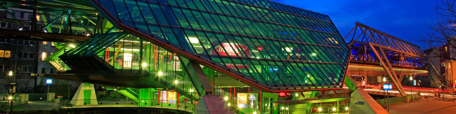 A modern glass building with a green roof and a ramp leading up to it.