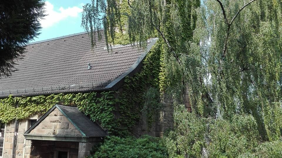 A stone church with a steeple and ivy-covered walls.