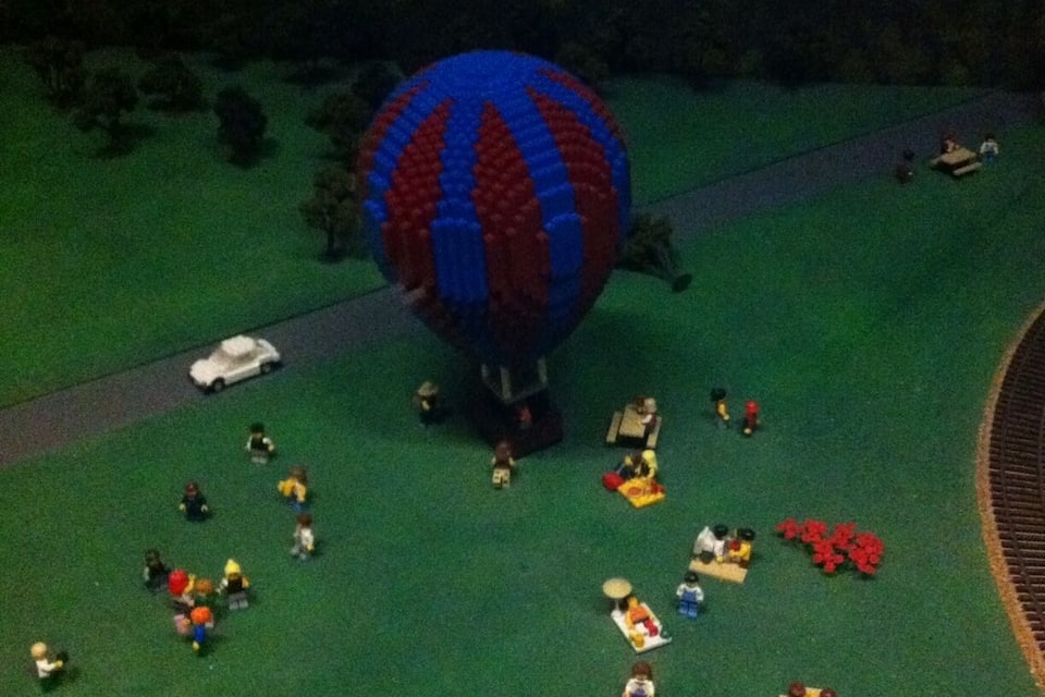 A model hot air balloon, miniature people, and a train track.