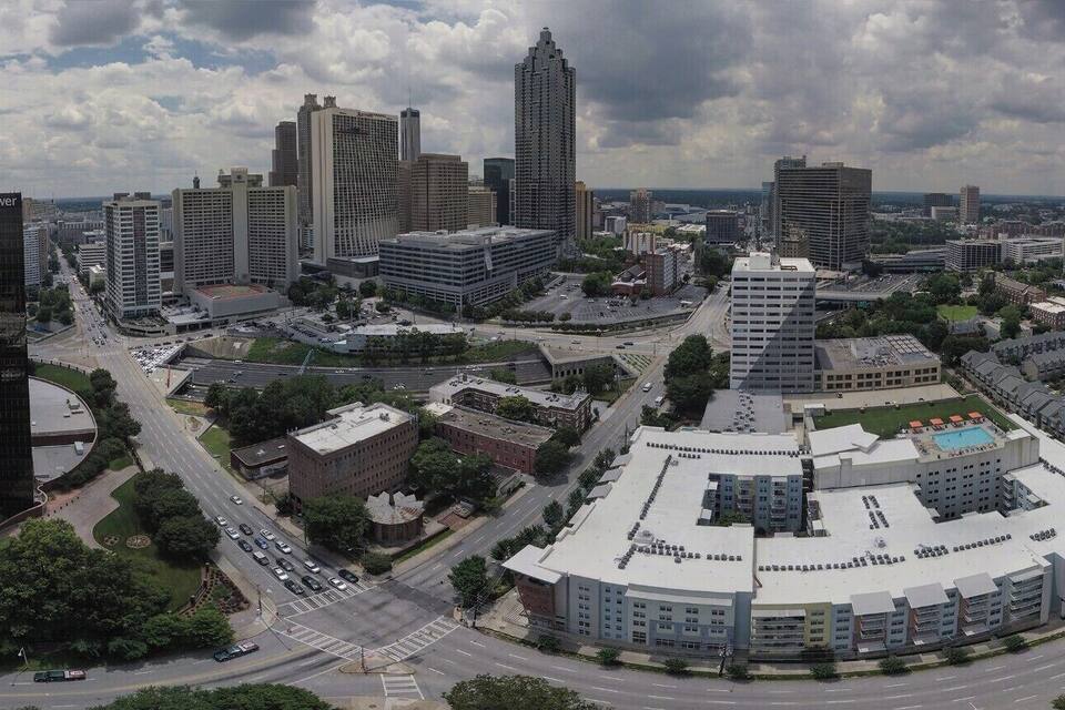 Paisagem urbana com edifícios modernos, um amplo estacionamento e um prédio redondo com telhado plano.
