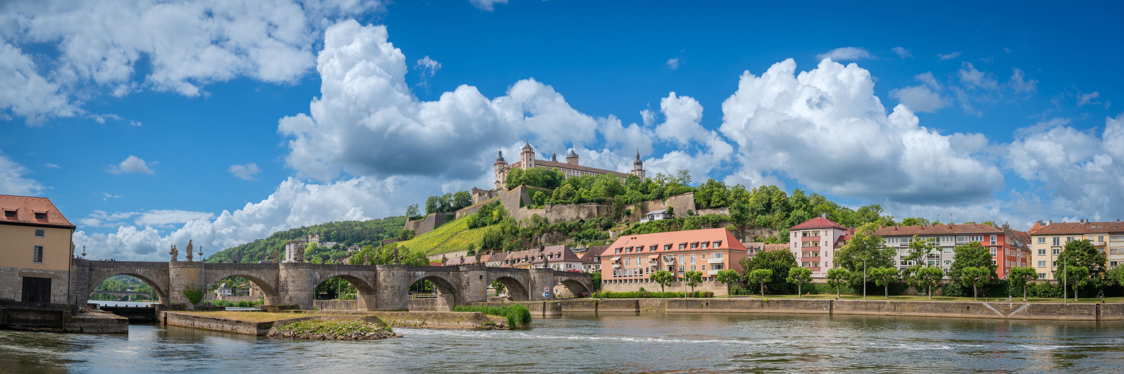 A stone bridge over a river, a castle on a hill, and buildings along the riverbank.