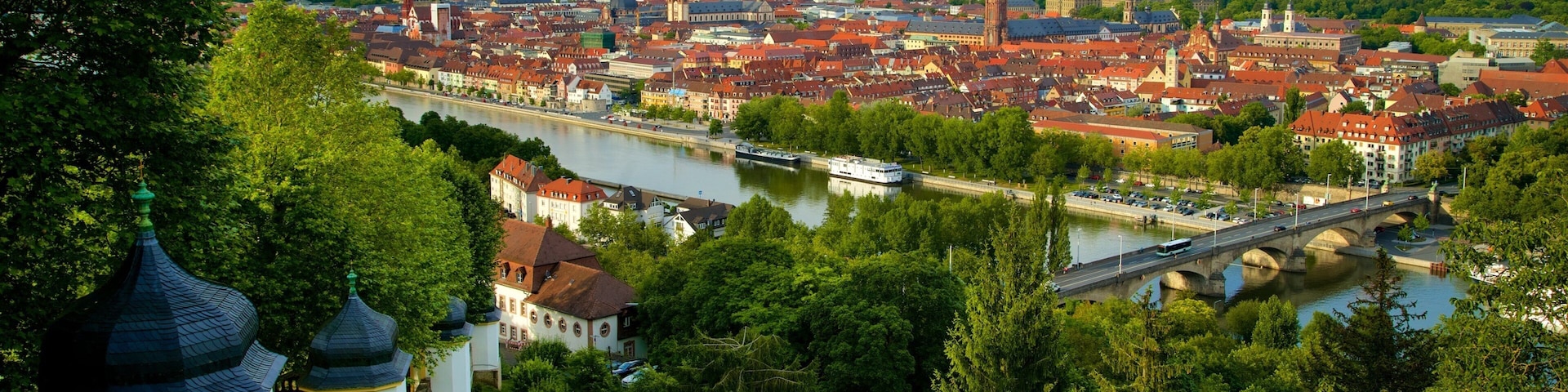A river flowing through a city with red-roofed buildings and a bridge.
