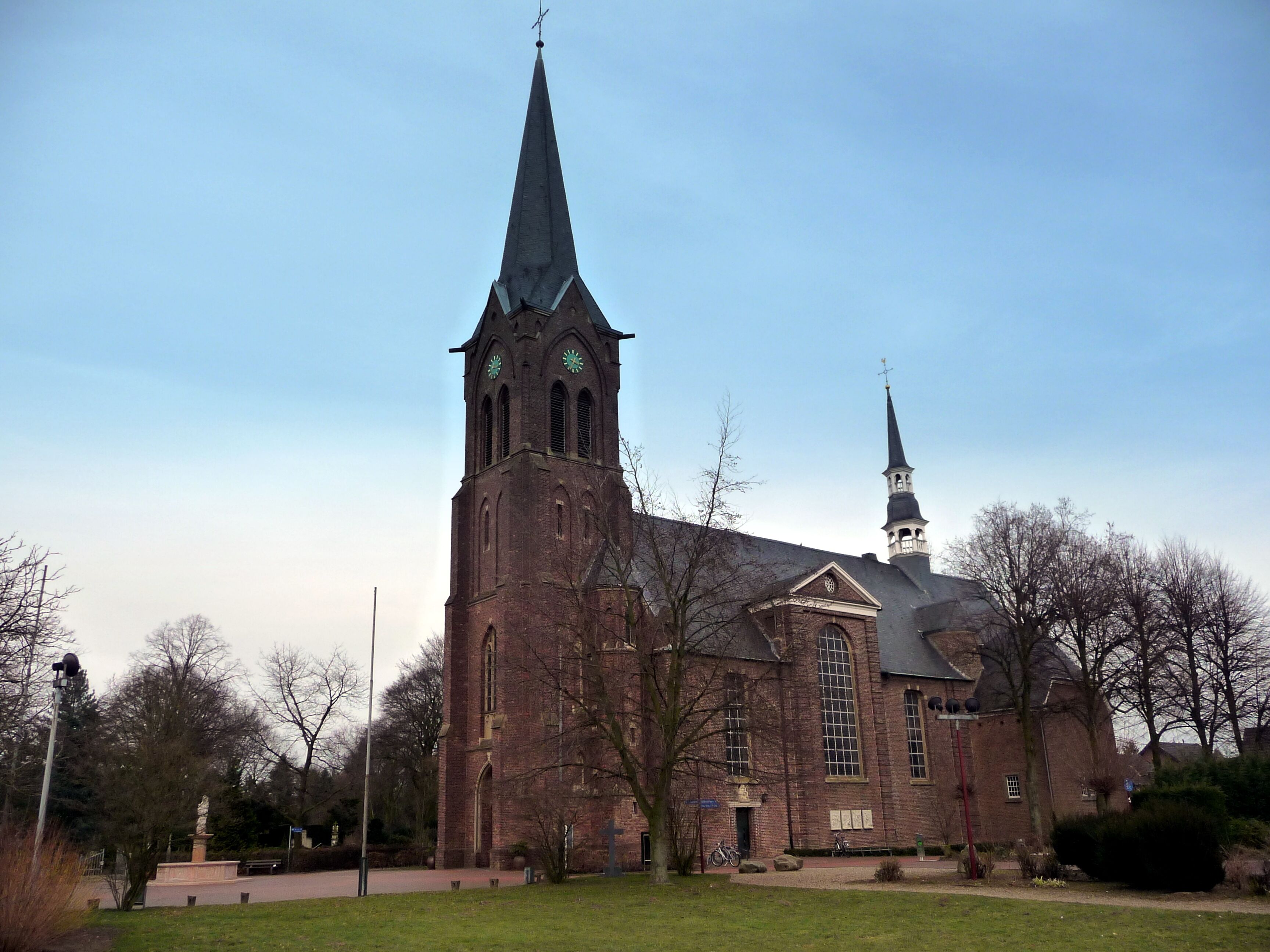 A large brick church with a tall steeple and a smaller spire.