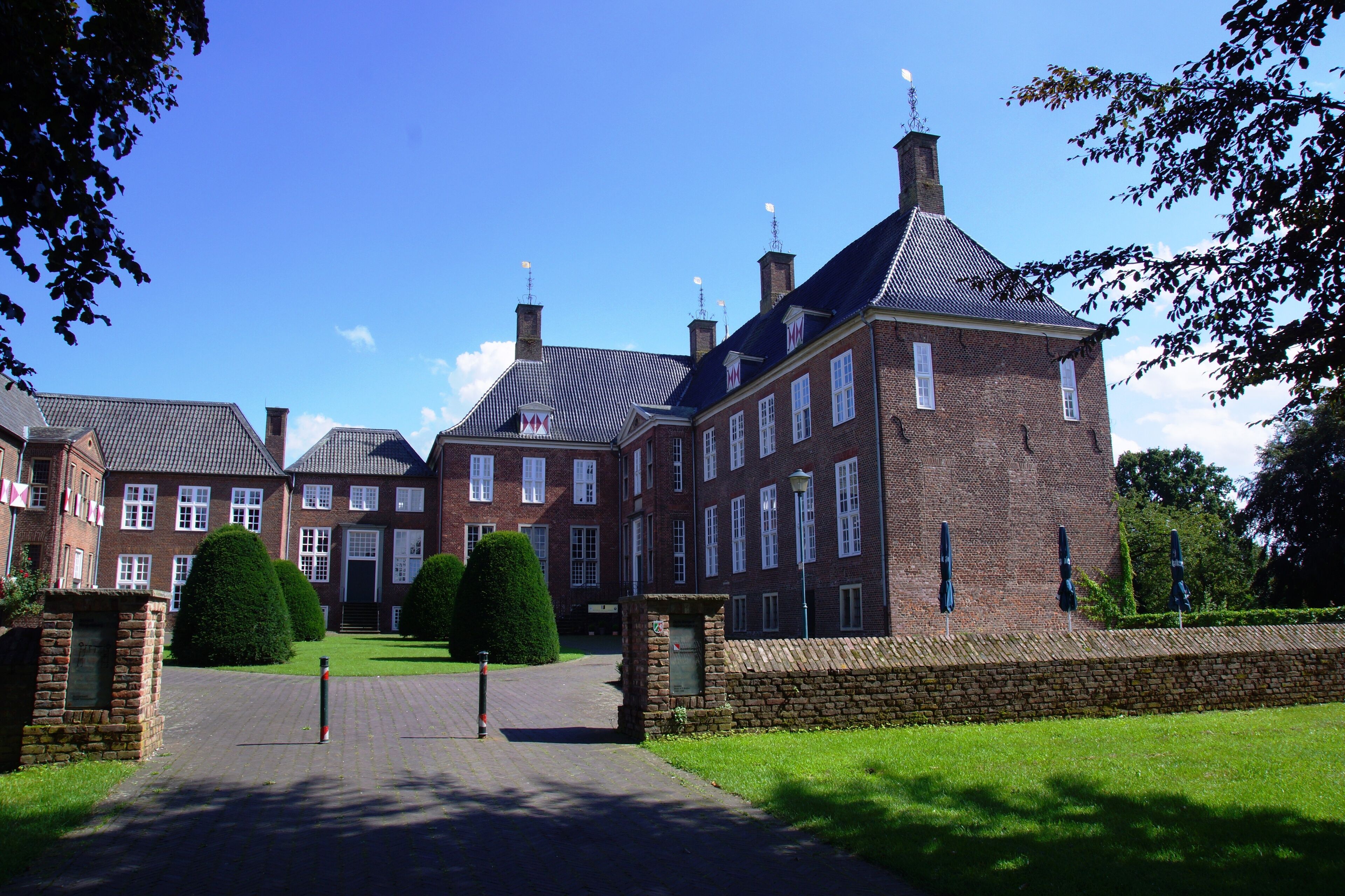 A large brick building with multiple chimneys and a paved entrance.