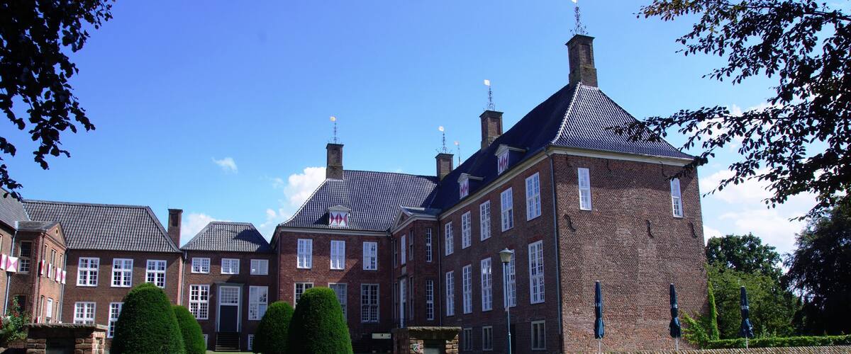 A large brick building with multiple chimneys and a paved entrance.
