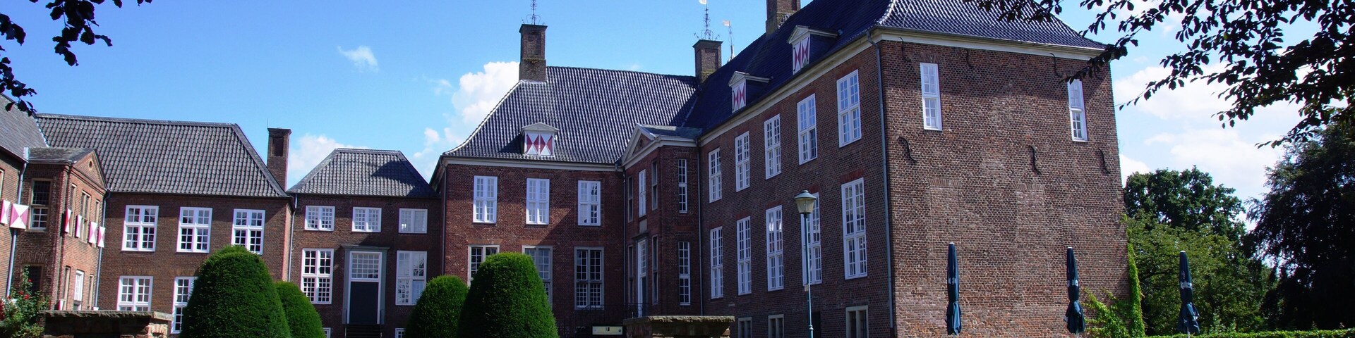A large brick building with multiple chimneys and a paved entrance.