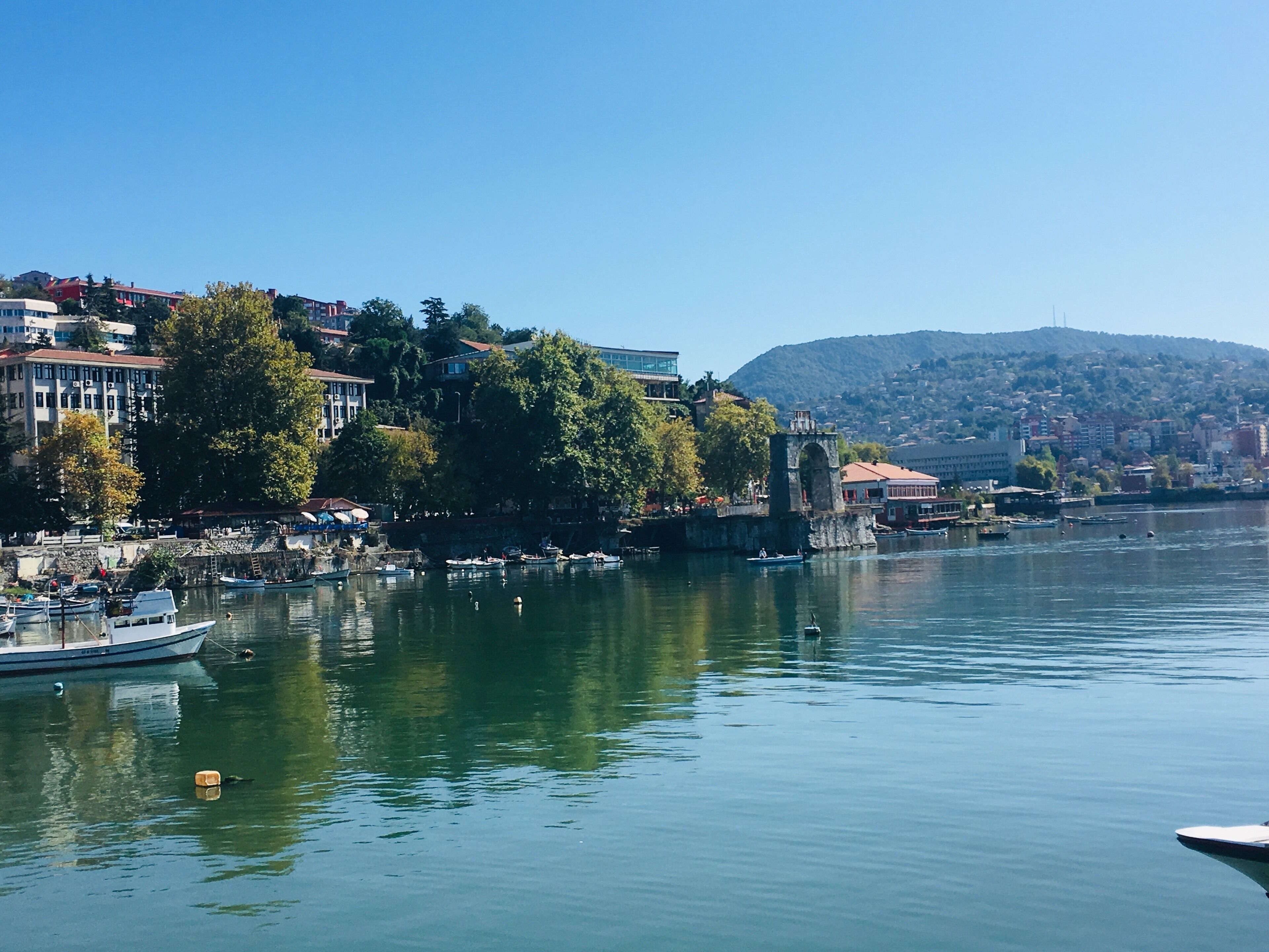 A calm river with boats, a bridge, and buildings along the riverbank.