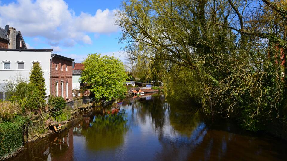 A calm river with buildings and trees along the banks.